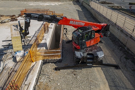 Roter Manitou-Teleskoplader mit ausgefahrenem Ausleger arbeitet auf einer Baustelle