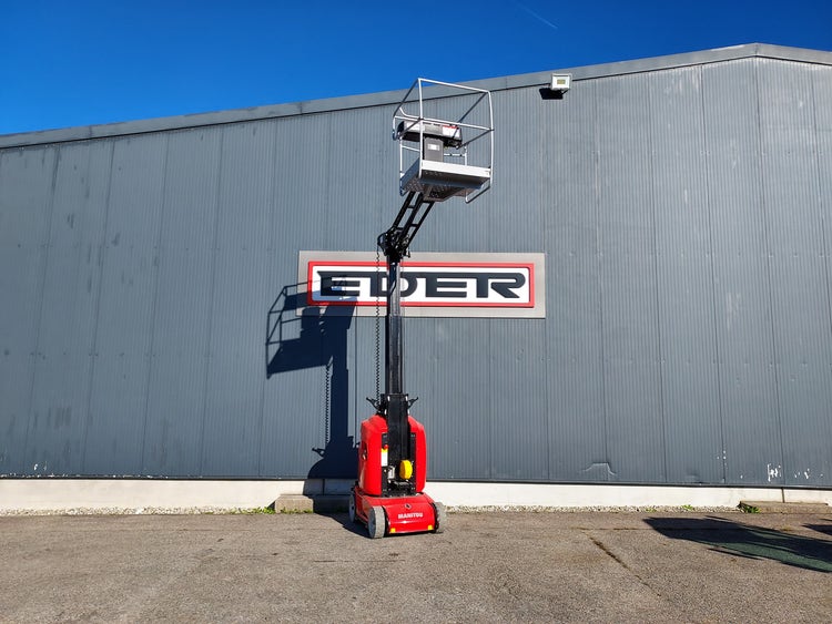 Frontale Ansicht einer ausgefahrenen Manitou Hubarbeitsbühne mit erhobener Arbeitsplattform vor einer Industriehalle mit EDER-Schriftzug.
