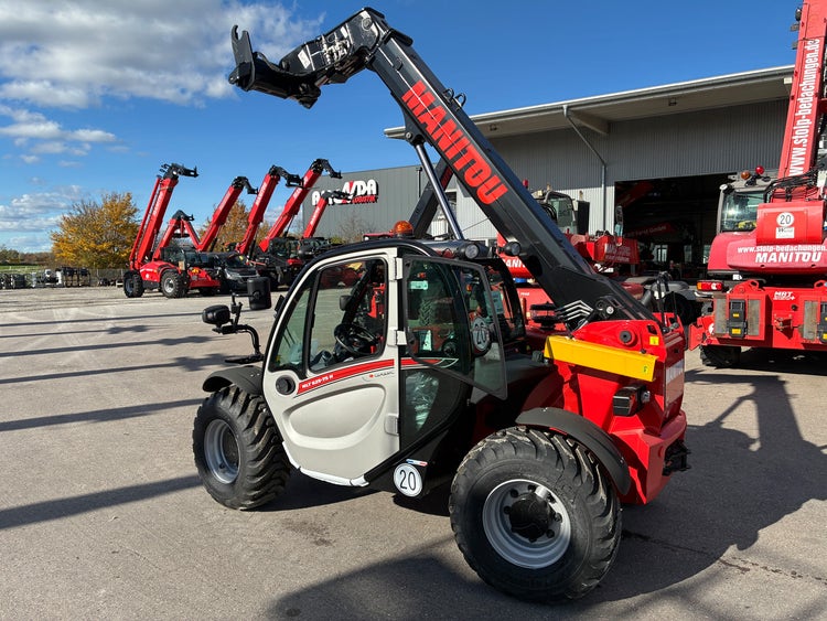 Seitenansicht des Manitou MLT 625 75K mit ausgefahrenem Teleskoparm vor der Werkstatt.