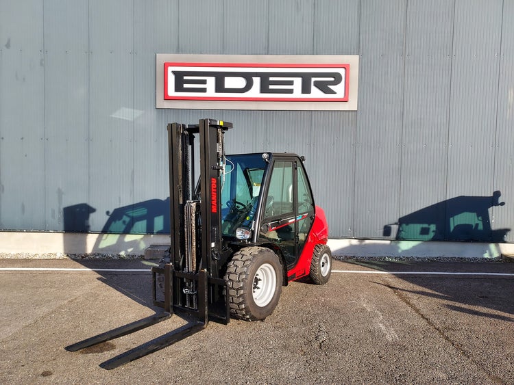 Schräg-frontale Ansicht eines roten Manitou MSI 30 Gabelstaplers mit gesenkter Gabelanlage vor dem EDER-Firmengebäude.