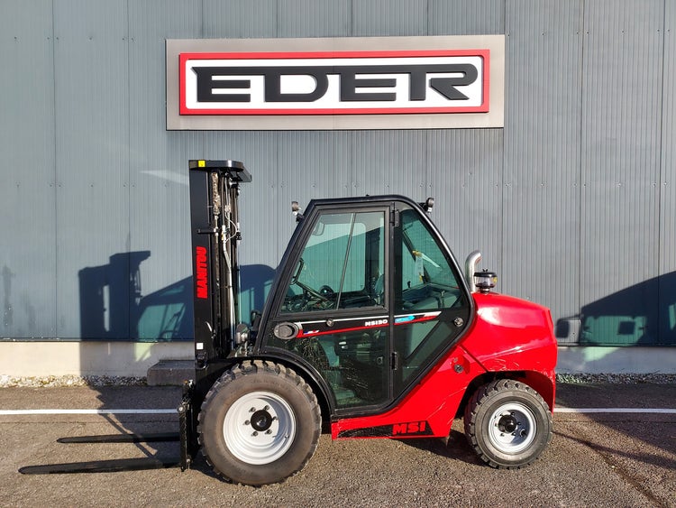 Seitliche Rückansicht eines Manitou MSI 30 Gabelstaplers mit gesenkten Gabeln vor einer Industriehalle mit EDER-Logo.