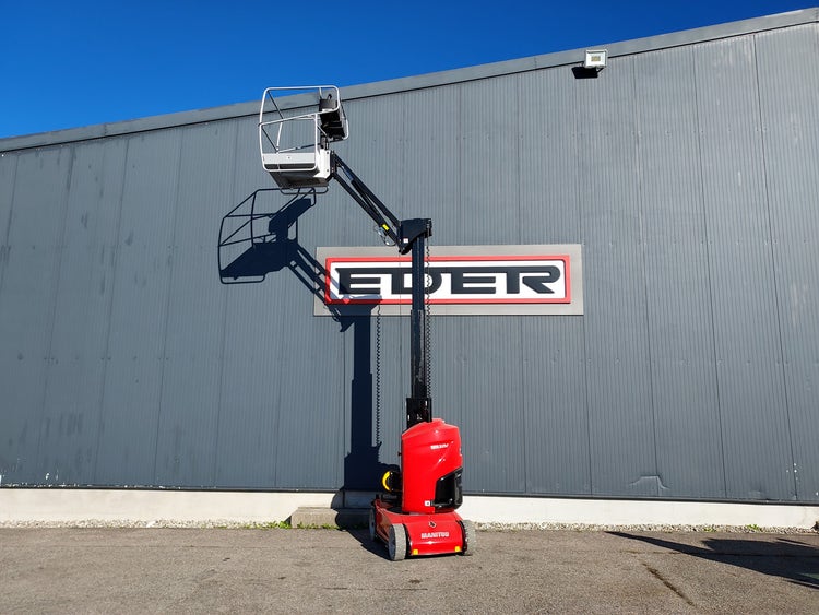 Manitou Hubarbeitsbühne mit seitlich ausgefahrenem Arm und erhobener Plattform, stehend vor einem Gebäude mit EDER-Logo.