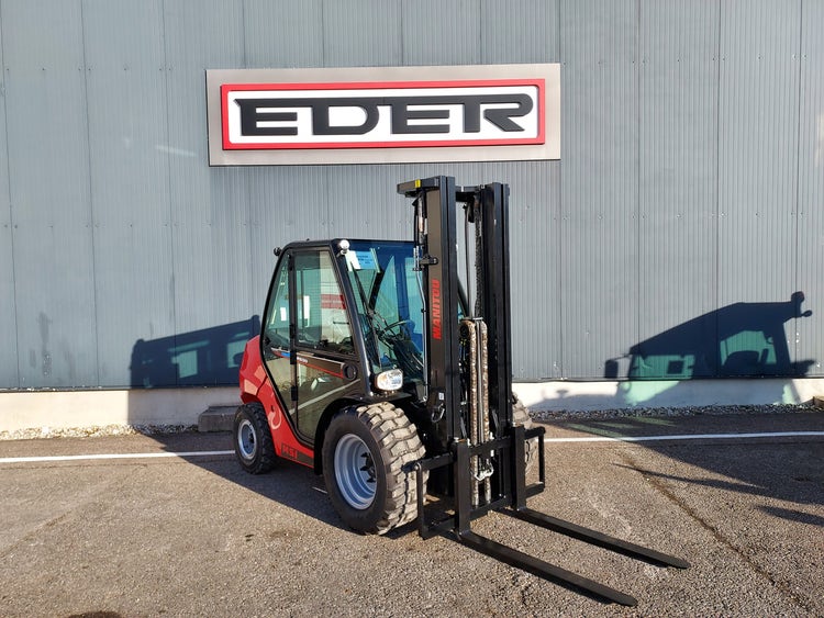 Schräg-frontale Ansicht eines roten Manitou MSI 30 Gabelstaplers mit gesenkten Gabeln vor einem Gebäude mit EDER-Logo.