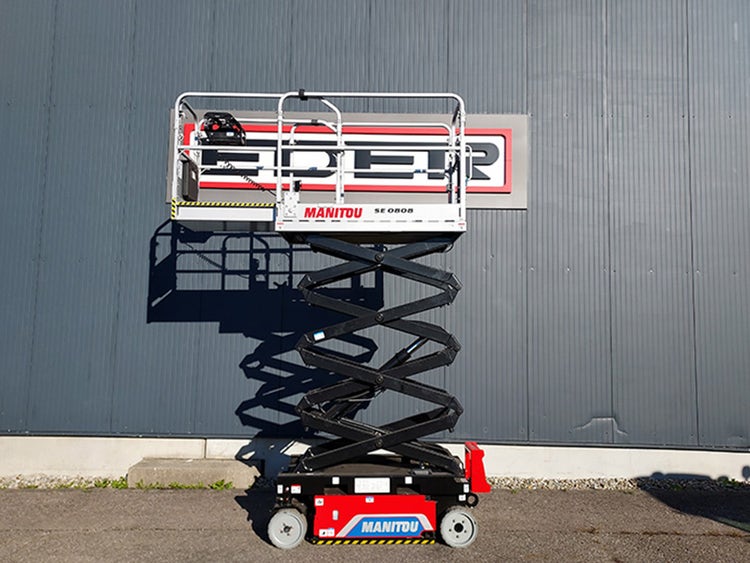 Ausgefahrene Manitou SE 0808 Scherenarbeitsbühne vor einer Hallenwand mit EDER-Logo, Plattform auf mittlerer Höhe.