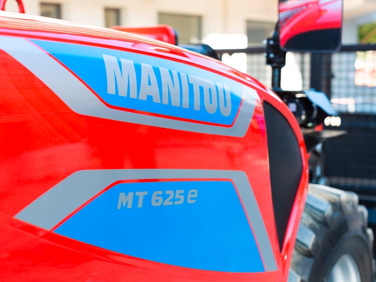 Nahaufnahme des roten Seitenteils eines Manitou Teleskopladers mit blauem Markenlogo und Modellbezeichnung MT 625e.