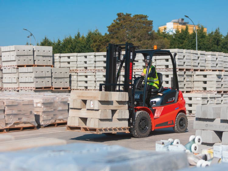Roter Manitou Gabelstapler transportiert Betonblöcke auf einen Lagerplatz