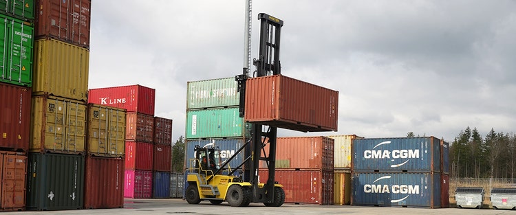 Hyster Containerstapler beim Anheben eines Frachtcontainers in einem Containerterminal.