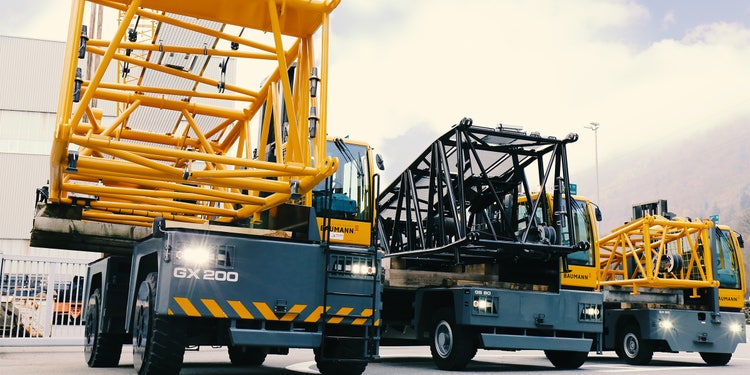 Mehrere gelb-graue Baumann-Seitenstapler transportieren große Metallkonstruktionen