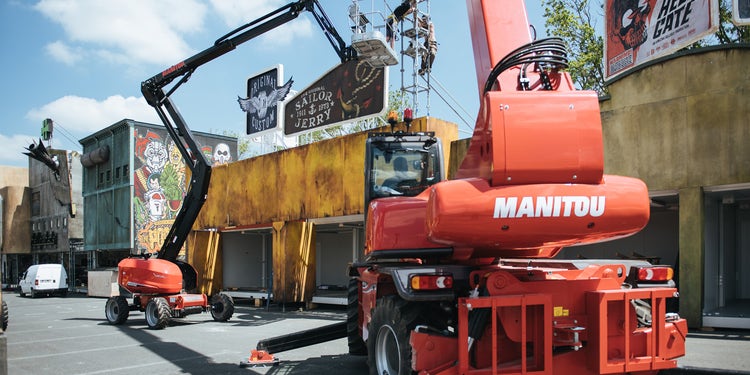 roter Manitou Teleskopstapler und Hebebühne heben Arbeiter an einer Hausfassade