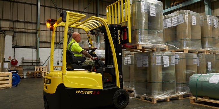 gelber Hyster Stapler nimmt eine Palette mit rollen auf