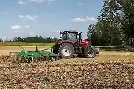 Bild eines roten Case Traktors beim Ackern